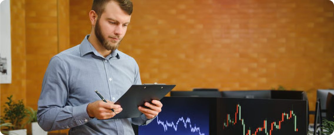 An operations specialist reviewing a status checklist in front of live monitoring dashboards